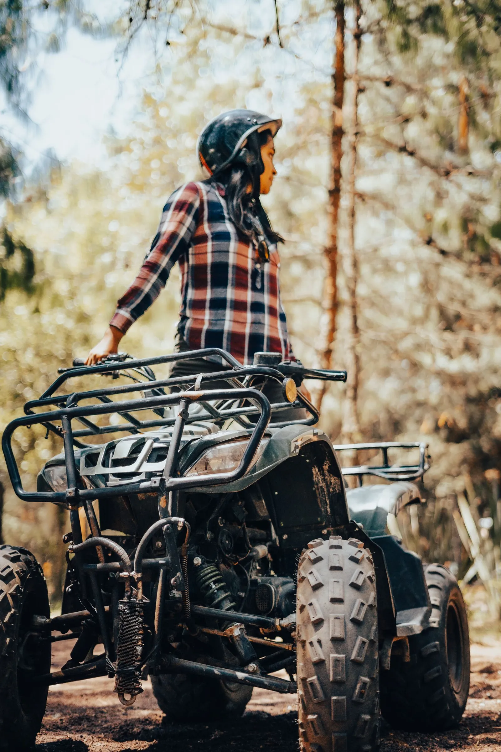 A helmeted rider beside a quad bike in woodland