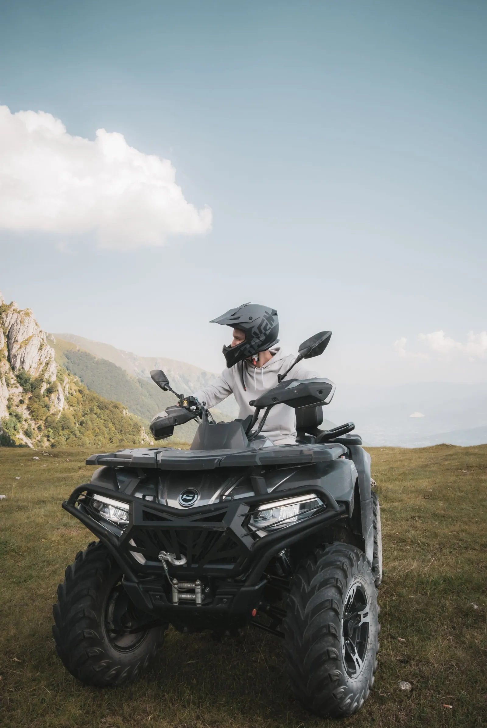 A helmeted rider on a quad bike in a hilly landscape
